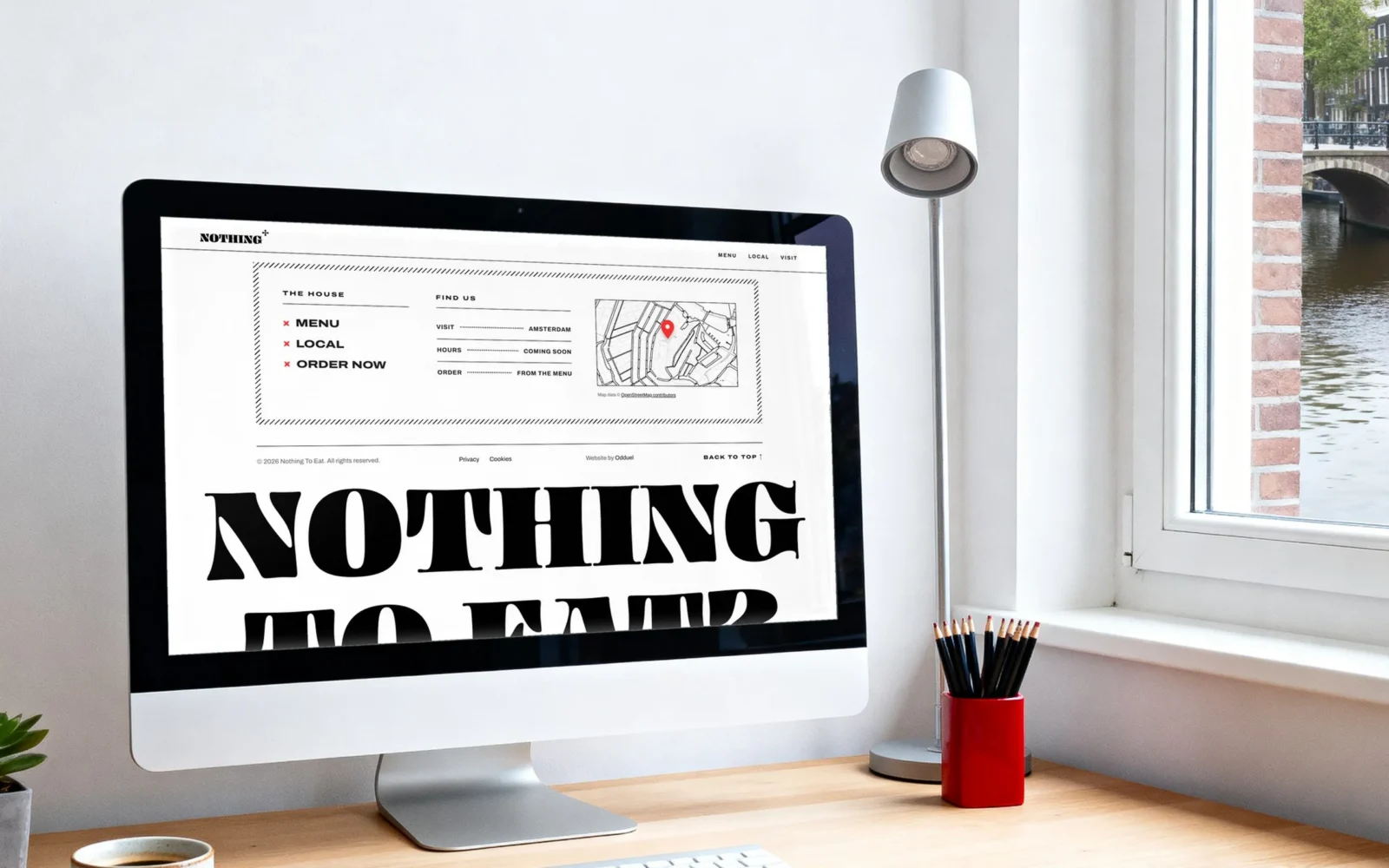 Uno schermo desktop in uno studio luminoso su un canale; mostra il footer del sito web di Nothing To Eat: i link della casa, una mappa disegnata dei canali con uno spillo rosso e «NOTHING TO EAT?» in grandissimo.
